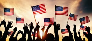 group people waving american flags back lit e1682994317686
